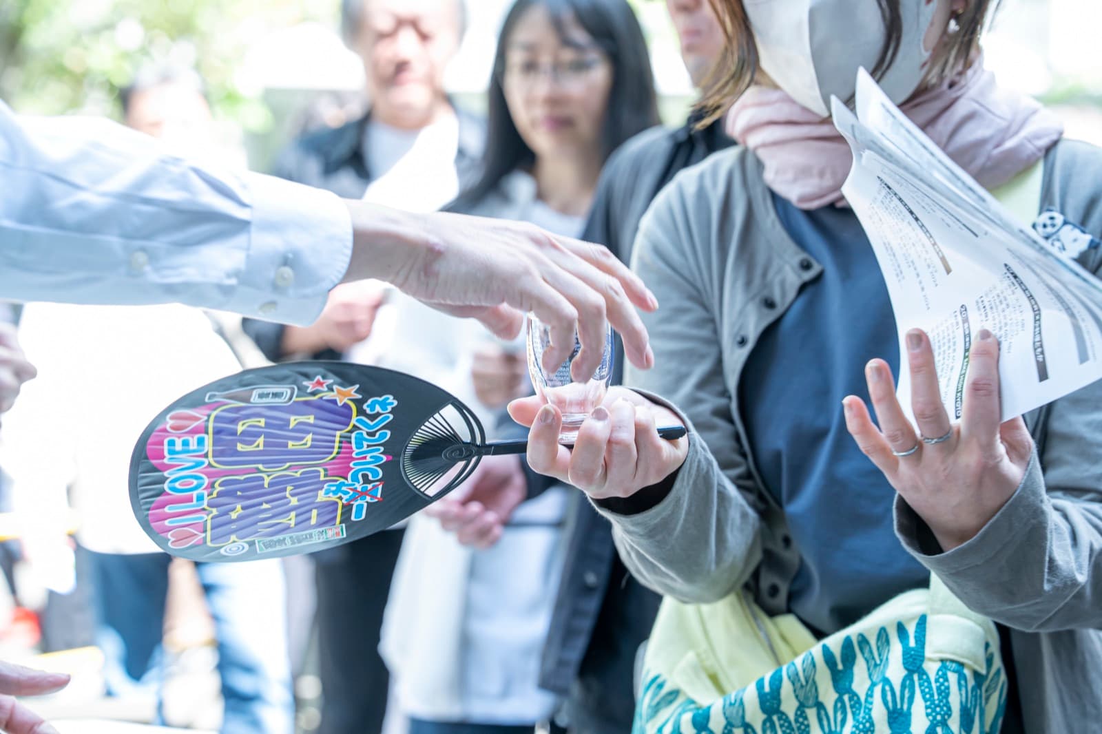 うちわとお猪口を持つ来場者